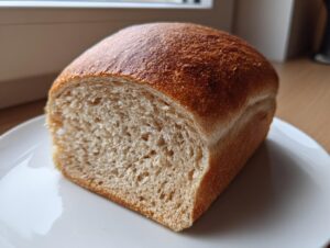 A close-up of a freshly baked whole wheat bread loaf, showing the soft interior crumb and golden-brown crust.