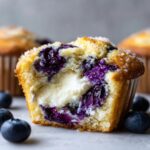Close-up of a blueberry cream cheese muffins cut in half showing the creamy filling and purple berries.