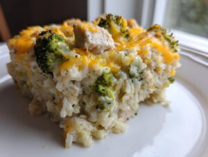 A close-up serving of creamy chicken broccoli rice casserole topped with melted cheddar cheese.