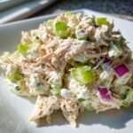 A close-up of a serving of creamy cottage cheese chicken salad mixed with celery and red onion chunks.