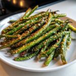 A plate piled high with roasted, crispy green beans topped with grated Parmesan cheese.