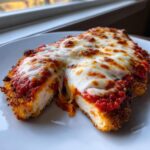 Cross-section view of Easy Chicken Parmesan showing crispy breading, white chicken meat, marinara sauce, and melted mozzarella cheese.