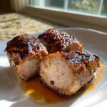 Three thick slices of glazed pork tenderloin recipe, showing a juicy interior and savory sauce.