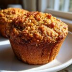 Close-up of a perfectly baked, golden brown honey bran muffin with a textured, sweet crumb topping.