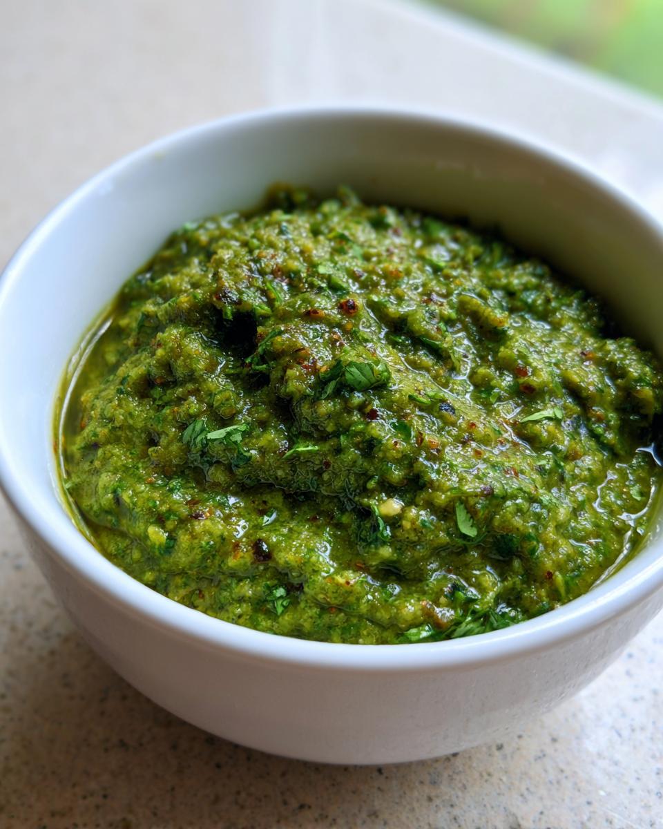 Close-up of thick, vibrant green tomato salsa texture in a small white bowl.