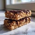 Two stacked homemade protein bars made with oats and drizzled with melted chocolate.
