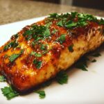 Close-up of a perfectly cooked salmon fillet coated in a shiny honey garlic glaze and topped with fresh chopped parsley.