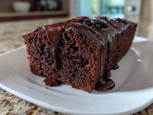A thick slice of dark, moist hot fudge brownie bread topped with dripping chocolate fudge sauce.