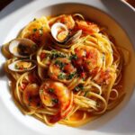 A vibrant plate of seafood pasta featuring large shrimp and clams tossed in a light sauce, garnished with parsley.