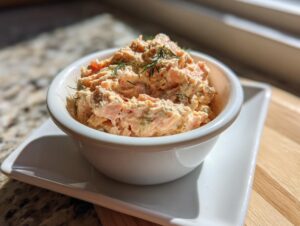 A small white bowl filled with creamy smoked salmon dip, garnished with fresh dill.