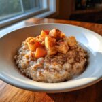 A close-up of creamy apple cinnamon oatmeal topped with diced apples and a dusting of cinnamon.