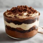A close-up of a Baileys Chocolate Cheesecake Trifle layered with chocolate cake, cream filling, and topped with chocolate crumbs.