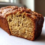 Close-up of a moist slice of the best banana bread showing its tender crumb and caramelized, sugary topping.