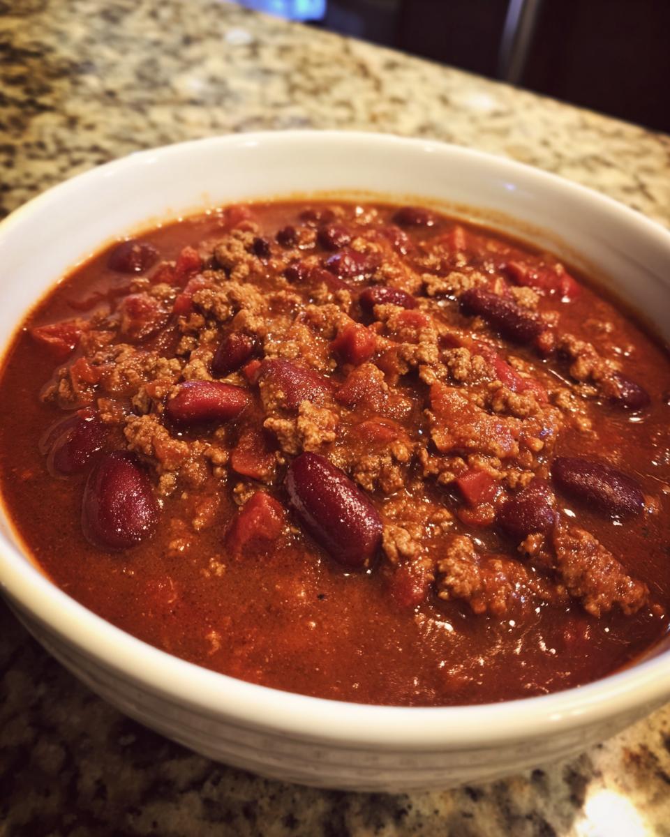 Close-up of a white bowl filled with rich, hearty chili featuring ground meat and dark red kidney beans.