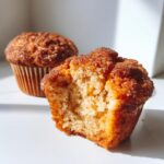 A close-up of a french toast muffins with a bite taken out, showing the soft interior and cinnamon sugar topping.