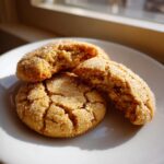 Close-up of soft, cracked brown butter sugar cookies rolled in sparkling sugar on a white plate.