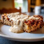 Close-up of a slice of golden-brown chicken fried steak smothered in creamy brown gravy.