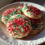 A stack of freshly baked Christmas sprinkle sugar cookies topped with red, green, and white nonpareils.