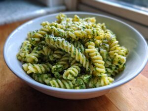 Close-up of creamy pesto pasta made with fusilli noodles, served in a white bowl.