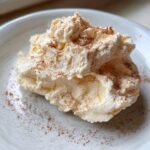 A dollop of creamy, whipped honey butter sprinkled generously with cinnamon on a white plate.