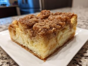 A close-up of a thick slice of amazing 1-night french toast casserole with a rich, brown cinnamon streusel topping.