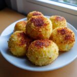 A plate of freshly pan-fried potato dumplings with a crispy, golden-brown exterior.