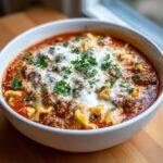 Close-up of a bowl of rich instant pot lasagna soup, featuring ground meat, pasta, melted cheese, and fresh parsley garnish.