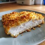 Cross-section of a juicy baked ranch chicken breast showing the white meat and golden, crispy breadcrumb topping.