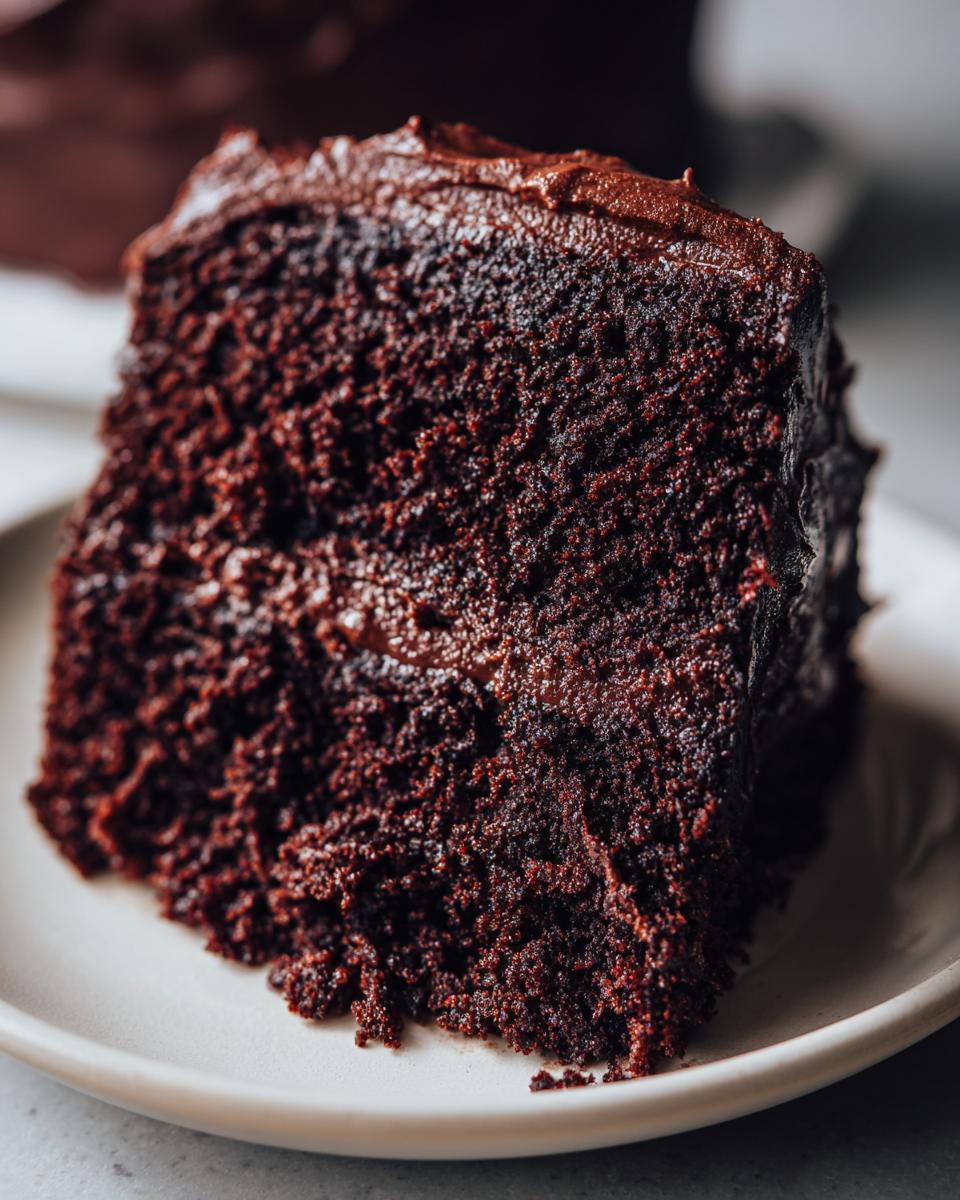 Extreme close-up showing the rich, dark, and moist crumb texture of a slice of chocolate cake.