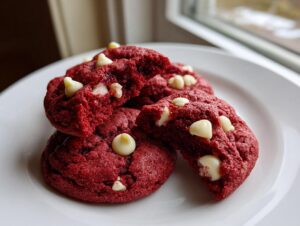 A stack of soft, bright red velvet cake mix cookies studded with white chocolate chips, one broken open.