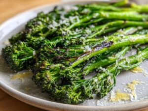 Close-up of bright green, roasted broccolini sprinkled with grated Parmesan cheese and lemon zest.