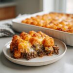 A generous slice of tater tot casserole featuring crispy tater tots, melted cheese, and a hearty ground beef base on a plate.