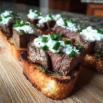 Close-up of perfectly cooked steak crostini topped with creamy cheese and chives, ready to serve.