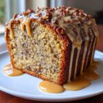 A thick slice of sweet Alabama pecan bread topped with a rich caramel glaze and chopped pecans.