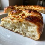 Close-up of a thick slice of white pizza showing gooey ricotta filling and browned mozzarella topping.