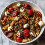 Close-up overhead view of amazing caprese pasta salad featuring rotini pasta, cherry tomatoes, mozzarella balls, and balsamic glaze.