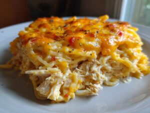 A close-up serving of creamy chicken spaghetti topped with melted, browned cheddar cheese.