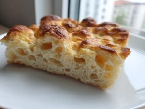 Close-up of a thick slice of golden-brown cottage cheese bread showing its airy, porous interior texture.