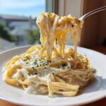 A fork lifts creamy fettuccine pasta coated in rich olive garden alfredo sauce, garnished with parsley.