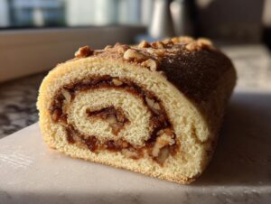 Close-up of a freshly baked Italian nut roll cookies log showing the swirl of nut filling and sponge cake.