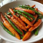 Close-up of vibrant Honey Glazed Carrots and Green Beans tossed together in a white serving bowl.