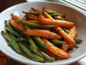 A white bowl filled with vibrant, glossy Honey Glazed Carrots and Green Beans, glistening with sauce.