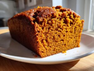 Close-up of a thick slice of moist Sweet Potato Cinnamon Bread showing its rich orange color and soft crumb texture.