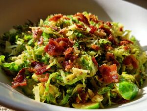 Close-up of Sautéed Shredded Brussels Sprouts topped generously with crumbled, crispy bacon pieces.